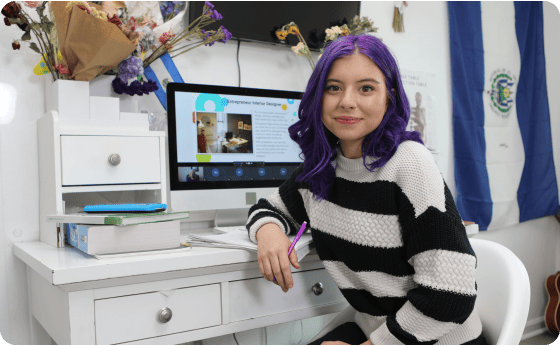 A woman with purple hair is seated at a desk, focused on her computer screen, creating a vibrant workspace.